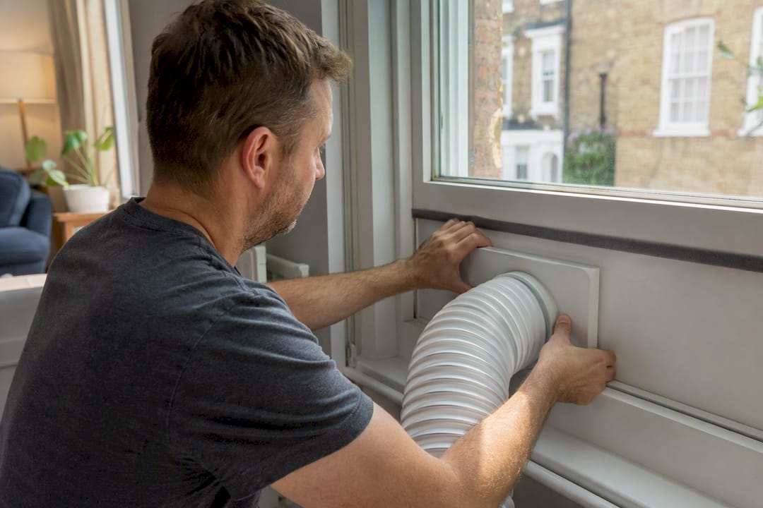 Hands fitting portable AC exhaust hose into window vent kit