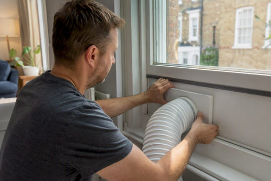 Hands fitting portable AC exhaust hose into window vent kit